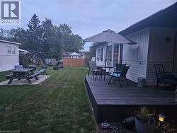 Expansive backyard with a wooden deck featuring a sliding glass door, white vinyl siding, and a partial privacy fence - 