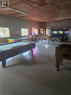 Spacious recreation room featuring a distinctive slatted wood ceiling, multiple windows, fluorescent lighting, and durable flooring - 