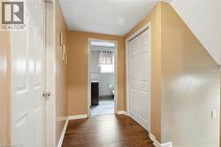 Hallway featuring wood-finish flooring, light tan wall paint, and white baseboards - 