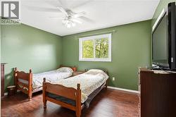 Room featuring wood-finish flooring, a white ceiling fan with integrated lighting, and a white-framed window - 