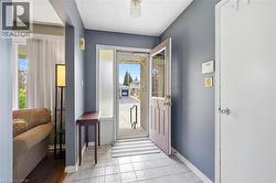 Entrance foyer featuring square tile flooring, a solid core door, and an adjacent sidelight with reeded glass - 