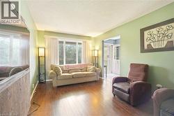 Spacious living area featuring wood-finish flooring, a large window with vertical blinds, and a wide entryway - 