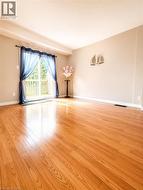 Spacious room featuring wood-finish flooring and neutral wall tones - 