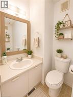 Bathroom featuring a vanity with an integrated sink and base cabinetry, a wood-frame mirror, an overhead light fixture, and tile flooring - 