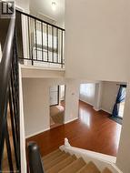 Multi-level interior featuring wood-finish flooring, a carpeted staircase with a dark wood handrail, and a second-level laundry area with built-in cabinetry - 