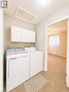 Dedicated laundry area featuring overhead cabinetry, built-in dryer connection, and an attic access panel - 