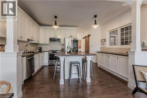 Bright kitchen featuring white cabinetry, stainless steel appliances, dark countertops, and wood-finish flooring - 2121 Prospect Street, Burlington, ON - Indoor Photo Showing Kitchen With Upgraded Kitchen