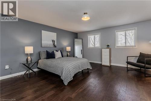 Spacious room featuring dark wood-finish flooring, light gray walls, and a contrasting accent wall - 2121 Prospect Street, Burlington, ON - Indoor Photo Showing Bedroom