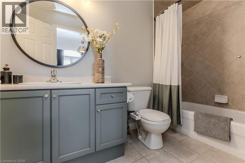 Bathroom featuring a vanity with blue-gray shaker-style cabinetry, a white countertop, and a circular wall mirror - 2121 Prospect Street, Burlington, ON - Indoor Photo Showing Bathroom