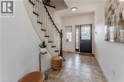 Entry foyer featuring a dark-paneled door with sidelight and transom, an interior curved staircase with dark wood treads and white balusters, and a tiled floor - 2121 Prospect Street, Burlington, ON - Indoor Photo Showing Other Room