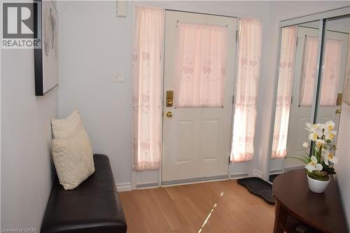 Entryway featuring light wood-finish flooring, a white entry door with frosted glass, and sliding mirrored closet doors - 28 Lemon Grass Street, Kitchener, ON - Indoor