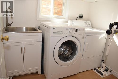 Dedicated laundry area featuring a stainless steel utility sink with a high-arch faucet, white cabinetry, and light wood-finish flooring - 28 Lemon Grass Street, Kitchener, ON - Indoor Photo Showing Laundry Room