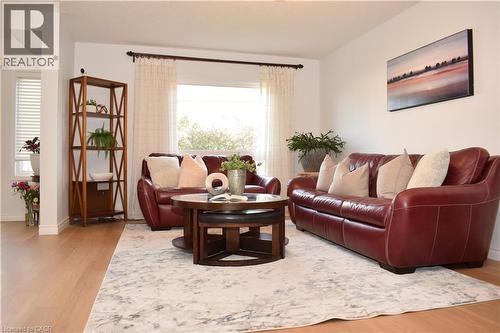 Bright living space featuring light wood-finish flooring, a large window with sheer drapes, and white wall finishes - 28 Lemon Grass Street, Kitchener, ON - Indoor Photo Showing Living Room