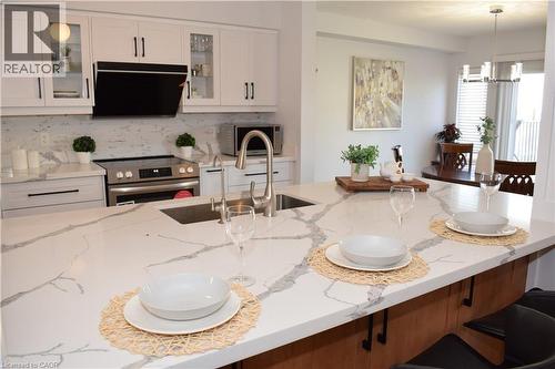 Expansive kitchen island featuring a waterfall-edge countertop, integrated sink, and seating - 28 Lemon Grass Street, Kitchener, ON - Indoor