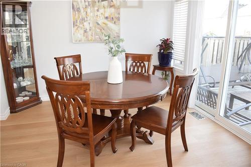 Dining area featuring light wood-finish flooring, a glass display cabinet, and a sliding glass door to an outdoor patio - 28 Lemon Grass Street, Kitchener, ON - Indoor Photo Showing Dining Room