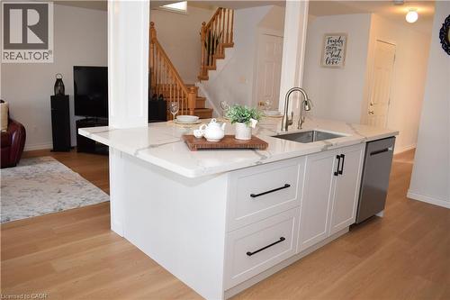 Kitchen island with white shaker cabinetry, an undermount stainless steel sink, and a stainless steel dishwasher - 28 Lemon Grass Street, Kitchener, ON - Indoor Photo Showing Kitchen