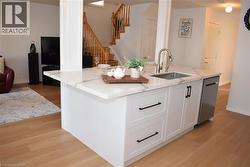 Kitchen island with white shaker cabinetry, an undermount stainless steel sink, and a stainless steel dishwasher - 