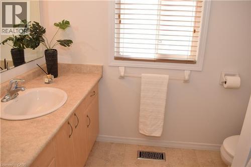 Bathroom featuring a vanity with an integrated sink, a light-toned countertop, and wood-finish cabinetry with curved hardware - 28 Lemon Grass Street, Kitchener, ON - Indoor Photo Showing Bathroom