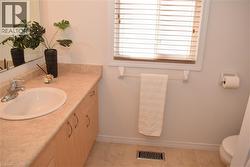 Bathroom featuring a vanity with an integrated sink, a light-toned countertop, and wood-finish cabinetry with curved hardware - 