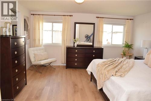 Bright room with light wood-finish flooring, white walls, and dual windows featuring white sashes and valances - 28 Lemon Grass Street, Kitchener, ON - Indoor Photo Showing Bedroom