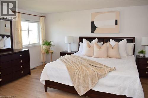 Spacious bedroom featuring wood-finish flooring and a large window with white trim - 28 Lemon Grass Street, Kitchener, ON - Indoor Photo Showing Bedroom