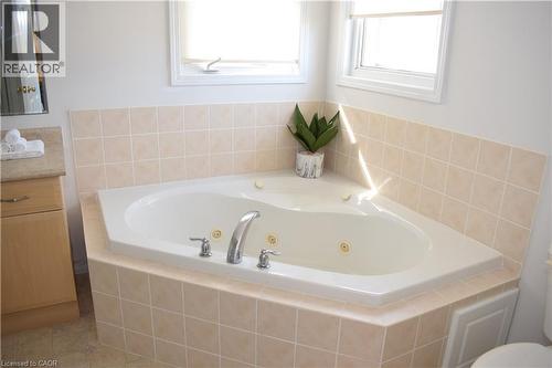 Corner jetted tub with chrome fixtures, surrounded by light-toned square tile - 28 Lemon Grass Street, Kitchener, ON - Indoor Photo Showing Bathroom
