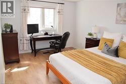 Bright room featuring a large window, light wood-finish flooring, and white baseboards - 