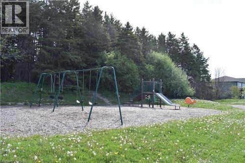 Outdoor recreational space featuring a swing set, playground structure with a slide, and a spring rider, all situated on a gravel surface - 28 Lemon Grass Street, Kitchener, ON - Outdoor