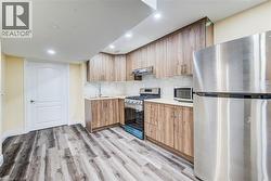Kitchen featuring wood-finish cabinetry, stainless steel appliances, and wood-finish flooring - 