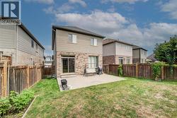 Expansive backyard featuring a concrete patio, sliding glass doors, and privacy fencing - 
