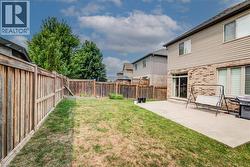 Expansive backyard featuring a wood privacy fence, a concrete patio, and a sliding glass door entry to the home - 