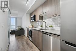 Modern kitchen featuring wood-finish cabinetry, stainless steel appliances, white subway tile backsplash, and light-toned countertops - 