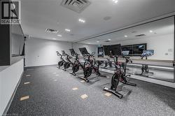 Fitness amenity featuring specialized flooring, mirrored wall, recessed lighting, and wall-mounted screens - 