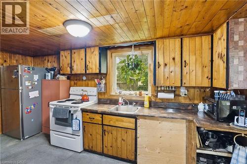Kitchen featuring wood paneling, wood-finish cabinetry, built-in sink, window, and overhead lighting - 834 Mohawk Road E, Hamilton, ON - Indoor Photo Showing Kitchen
