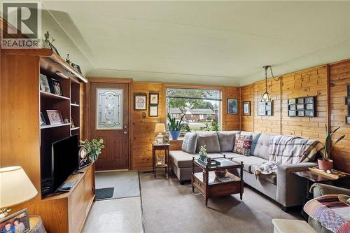 Living area featuring wood paneling, a front entry door with decorative glass, and a large bay window - 834 Mohawk Road E, Hamilton, ON - Indoor Photo Showing Living Room