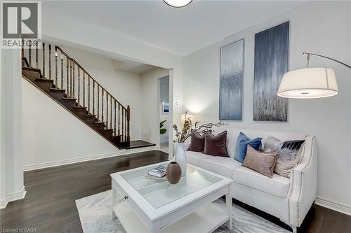 Dark wood-finish flooring complements a staircase with dark wood treads and a spindle banister - 598 Bessborough Drive, Milton, ON - Indoor Photo Showing Living Room