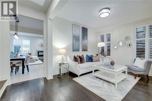 Living room featuring dark wood-finish flooring and white plantation shutters - 598 Bessborough Drive, Milton, ON - Indoor Photo Showing Living Room
