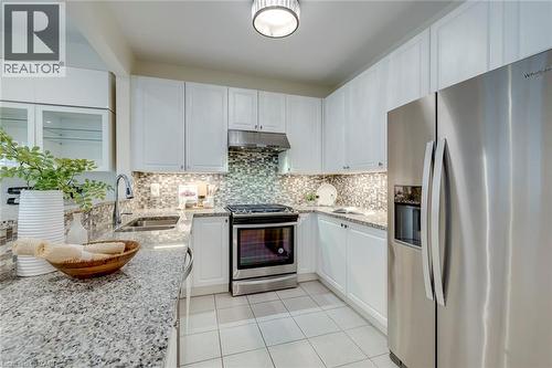 Modern kitchen featuring white cabinetry, granite countertops, stainless steel appliances, a mosaic tile backsplash, and recessed lighting - 598 Bessborough Drive, Milton, ON - Indoor Photo Showing Kitchen With Double Sink With Upgraded Kitchen