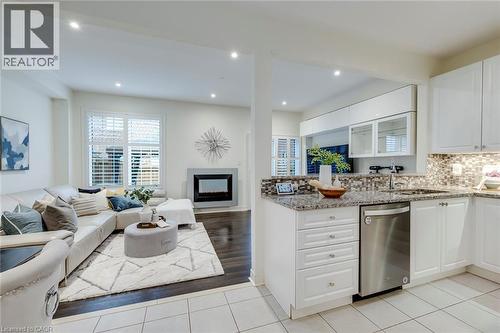 Kitchen featuring granite countertops, mosaic tile backsplash, white cabinetry, and stainless steel dishwasher - 598 Bessborough Drive, Milton, ON - Indoor Photo Showing Kitchen With Fireplace With Upgraded Kitchen