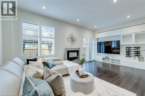 Living area featuring dark wood-finish flooring, recessed lighting, and white plantation shutters on windows and a glass-paneled door - 598 Bessborough Drive, Milton, ON - Indoor Photo Showing Living Room With Fireplace