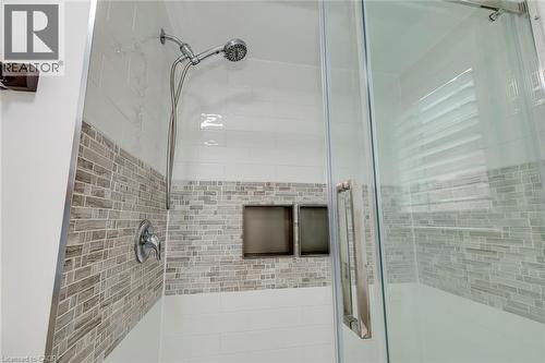 Glass-enclosed shower featuring white subway tile, a mosaic tile accent band, dual recessed shower niches, a handheld shower fixture, and a single-handle temperature control - 598 Bessborough Drive, Milton, ON - Indoor Photo Showing Bathroom