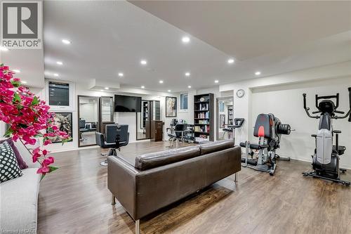 Spacious lower level featuring wood-finish flooring, recessed lighting, multiple windows, and a dedicated fitness area - 598 Bessborough Drive, Milton, ON - Indoor Photo Showing Gym Room