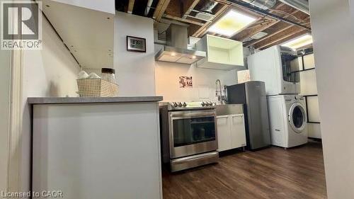 Stainless steel range with matching range hood, stainless steel sink, wood-finish flooring, and white cabinetry - 598 Bessborough Drive, Milton, ON - Indoor Photo Showing Laundry Room