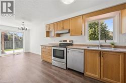Kitchen featuring wood-finish cabinetry, stainless steel appliances, and a double basin sink with a gooseneck faucet - 