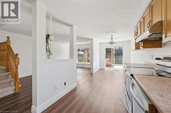 Open-concept kitchen and dining area featuring wood-finish flooring, light-toned cabinetry, and a black and stainless steel range - 