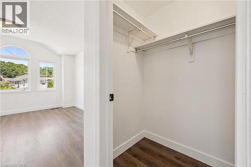 Spacious closet with built-in shelving and hanging rod, complemented by wood-finish flooring - 71 Peach Blossom Crescent, Kitchener, ON 