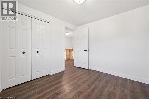 Interior space featuring wood-finish flooring, white walls, and a white ceiling with a flush-mount light fixture - 71 Peach Blossom Crescent, Kitchener, ON 