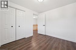 Interior space featuring wood-finish flooring, white walls, and a white ceiling with a flush-mount light fixture - 