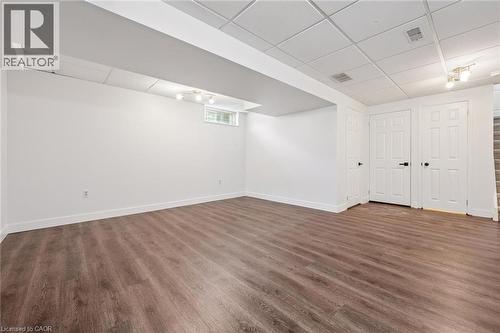 Spacious room featuring wood-finish flooring, white walls, and a drop ceiling - 71 Peach Blossom Crescent, Kitchener, ON 