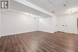 Spacious room featuring wood-finish flooring, white walls, and a drop ceiling - 